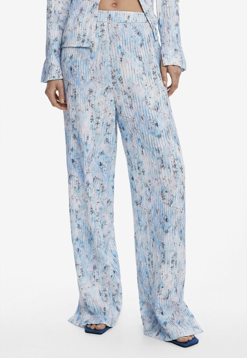 Pantalons légers et fluides, à motifs bleu et blanc, avec des rayures verticales et des accents floraux. Conception à jambes larges avec une taille confortable.