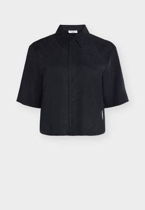 Camicia nera a maniche corte con bottoni, colletto appuntito e una piccola etichetta bianca sulla cucitura laterale destra.