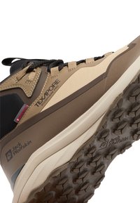 Scarpa da hiking beige e marrone con tomaia testurizzata, punta rinforzata e suola robusta con grip a motivo. Marchio sul lato.