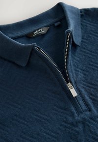 Navyblaues Polo-Shirt mit strukturiertem Muster, Reißverschluss und geripptem Kragen. Mit einem Metallreißverschluss mit rechteckigem Ziehband.