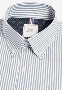Chemise à boutons avec des rayures verticales bleues et blanches, un col intérieur à pois navy contrastant, et une étiquette indiquant "next TAILORING."