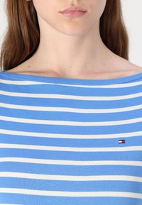 Blauw en wit gestreepte off-shoulder top van lichtgewicht stof, met een klein logoaccent op de linkerborst.