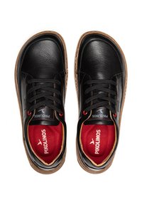 Zapatos de cuero negro con punteras redondeadas, cordones negros y acentos rojos en el interior. Presentan una suela texturizada y una plantilla con logotipo.