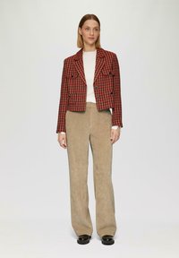 Rode en zwarte houndstooth blazer met twee voorzakken, dubbelgeknoopte knopen, gecombineerd met beige corduroy wijde broek.