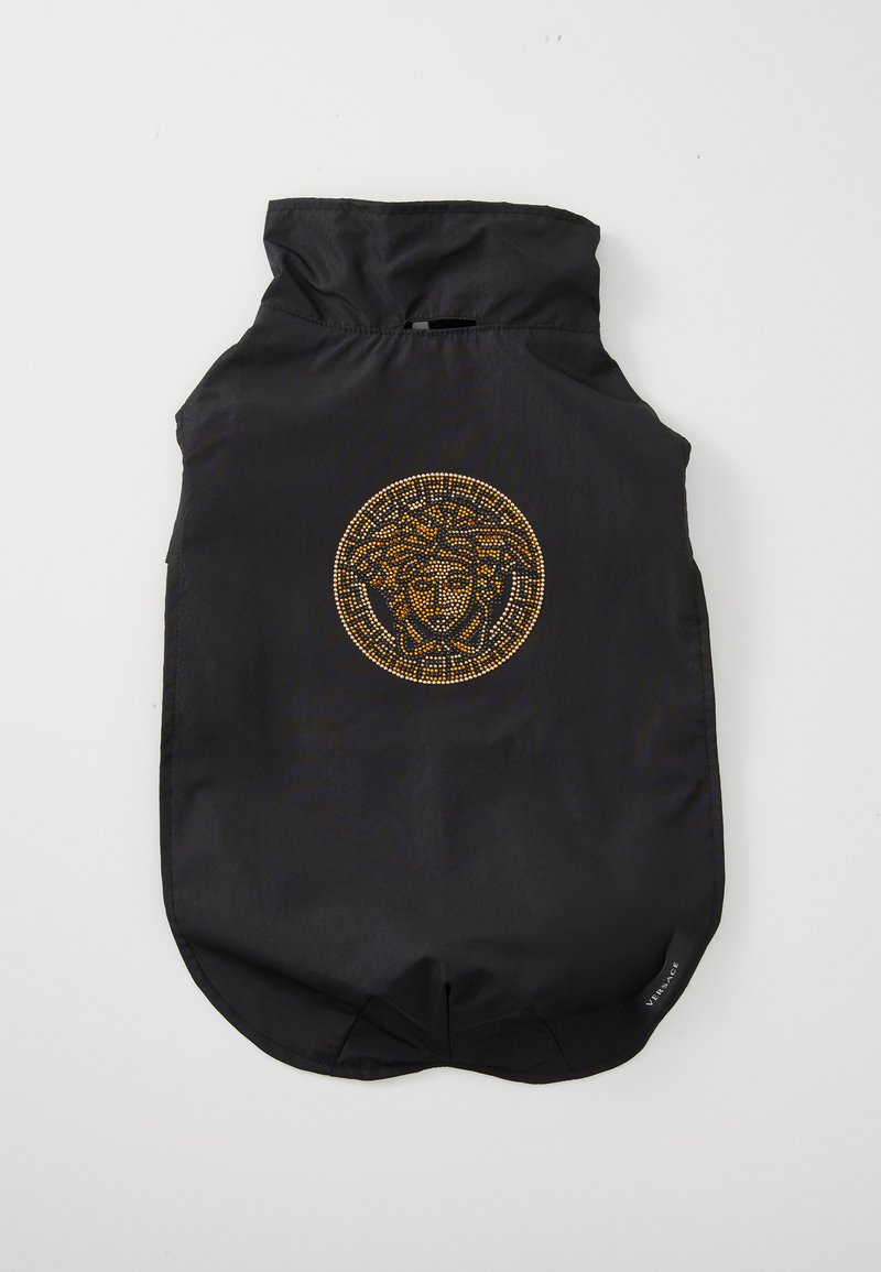 Svart tyghundrock med hög krage och ett cirkulärt design med guldfärgade nitar som föreställer ett ansikte på baksidan. Slät textur, sömlösa kanter.