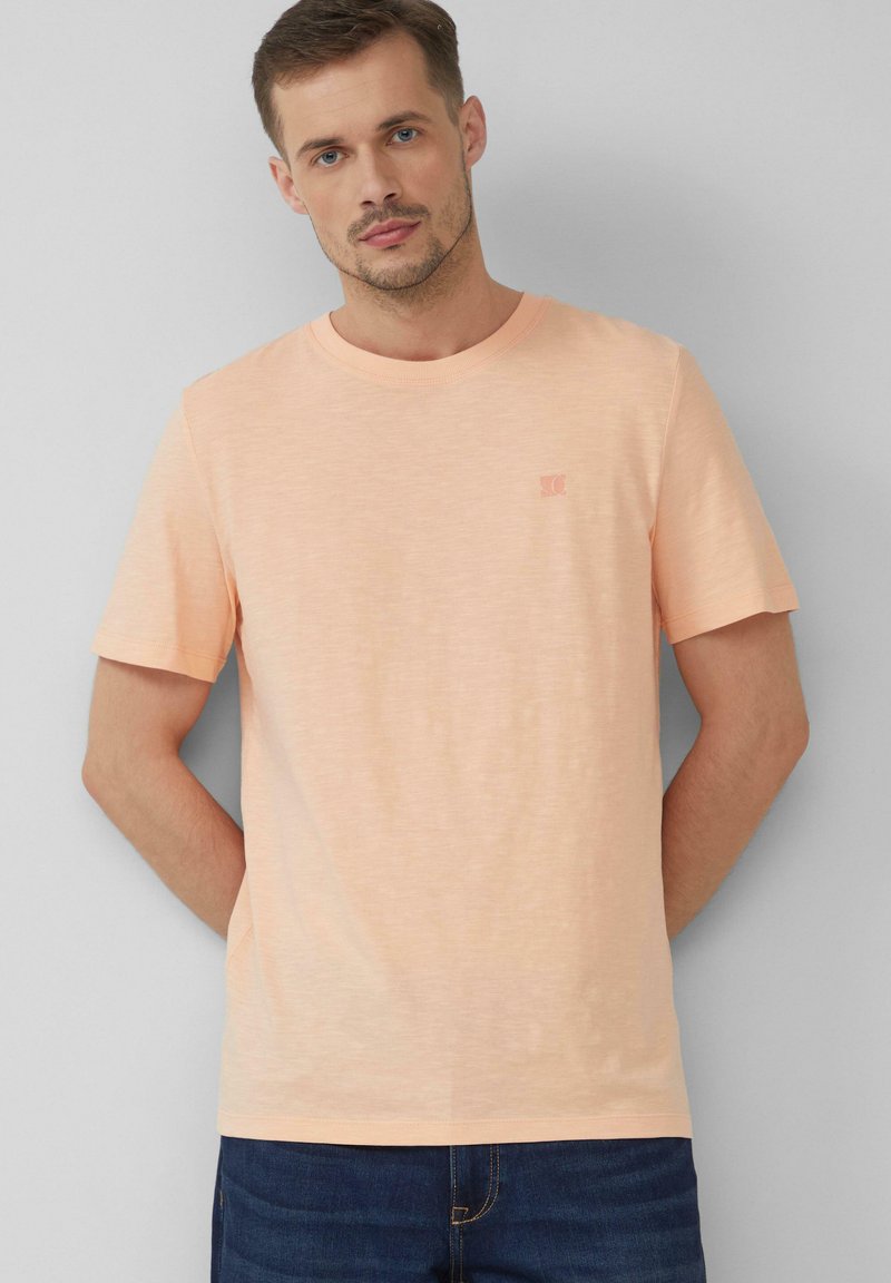 Perzikkleurig T-shirt met korte mouwen, gemaakt van een zachte, lichte katoenmix, met een subtiele logo op de borst en een klassieke ronde hals.