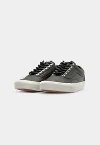 Zapatillas de cuero negro con suelas de goma blanca, que presentan cordones redondos negros y un diseño de panel lateral texturizado.
