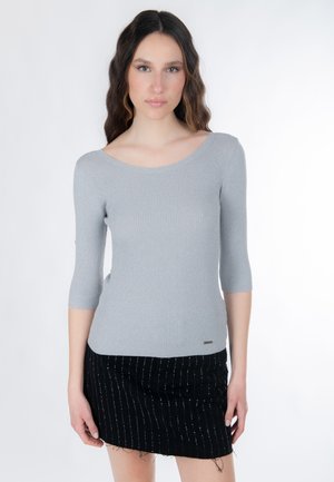 Top a maglia grigia chiaro con motivo a coste, maniche a tre quarti, scollo rotondo e un sottile dettaglio con logo all'orlo, abbinato a una minigonna nera.