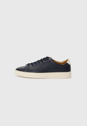 Navy leather sneaker with a rounded toe, cream rubber sole, and matching laces. Features a tan leather interior and subtle branding.