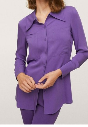 Camisa morada de manga larga con cuello puntiagudo, dos bolsillos frontales, textura suave y cierre de botones, usada sobre pantalones a juego.
