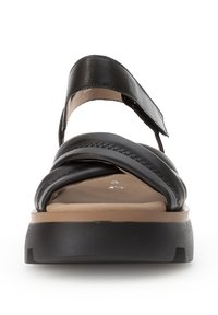 Czarne skórzane sandały z krzyżującymi się paskami i regulowanym zapięciem na kostce. Posiadają teksturowaną podeszwę oraz solidną, grubą, brązową platformę.