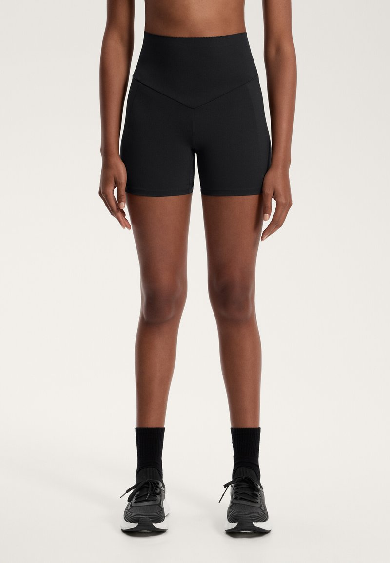 Visoko pasovi črni aktivni kratki hlače iz gladkega, raztegljivega materiala z žičnato zasnovo na pasu. Imajo prilegajoč kroj in minimalne šive.