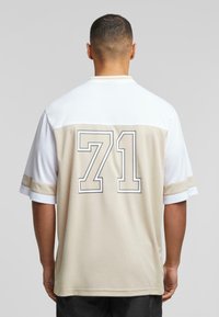 Sports jersey featuring a white upper and beige lower section, with a bold "71" printed on the back. Short sleeves and a smooth texture.