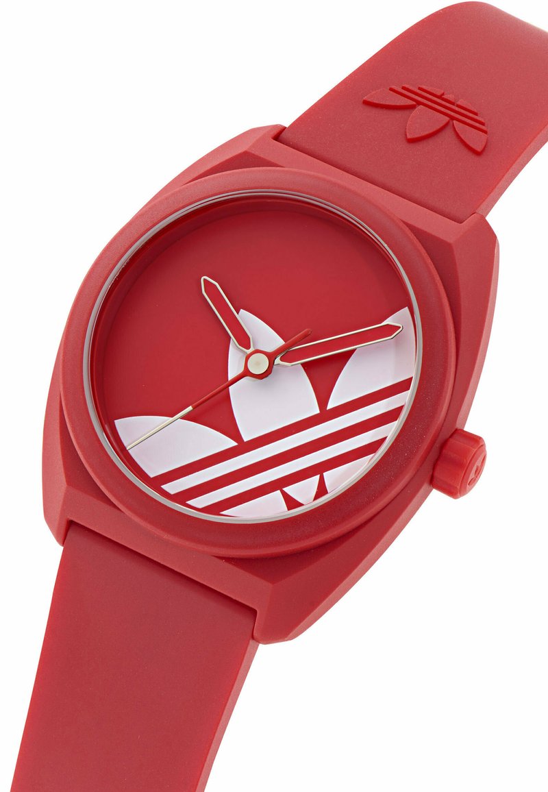 Rødt silikoneur med rund urskive, der har et hvidt logodesign og vandrette striber. Indeholder røde time- og minutvisere.