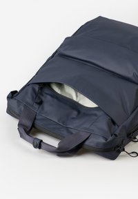Dunkelblauer gepolsterter Rucksack mit einer Reißverschlusstasche, der eine glatte Textur und zwei robuste Stoffgriffe zum Tragen aufweist.