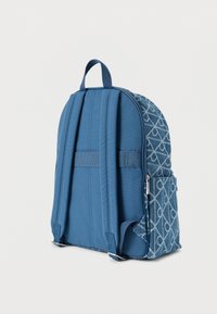 Μπλε σακίδιο με υφή σχεδίασης που παρουσιάζει γεωμετρικό μοτίβο στη μία πλευρά, με επενδεδυμένους ιμάντες και επάνω χερούλι για εύκολη μεταφορά.