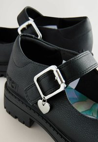 Czarne buty typu Mary Jane z ekoskóry, z mocną podeszwą, regulowanym zapięciem i dekoracyjnym serduszkiem. Posiadają wzorzystą wkładkę.