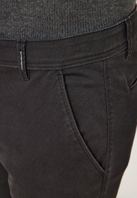 Schwarze Denim-Hosen mit glatter Textur, ausgestattet mit einer Vordertasche und einem Bund mit dezenten Nähten und Logo-Akzent.