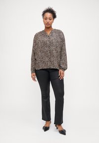 Μπλούζα με λεοπάρ σχέδιο, V-λαιμόκοψη και μακρύ μανίκι, σε συνδυασμό με μαύρο παντελόνι ίσιου σχεδίου και μαύρα παπούτσια με μυτερή μύτη. Λείος υφασμάτινος.