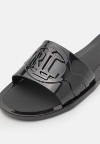 Sandale slide noire brillante avec logo RL en relief sur une large bride et semelle intérieure lisse et profilée.