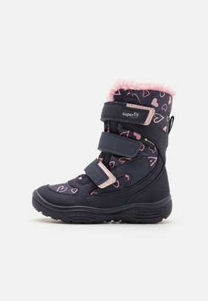 Sort vinterstøvle til børn med pink hjerte-mønstre, tre velcrolukninger og pink fleecenetting, der er synligt øverst.