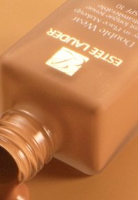 Estée Lauder Double Wear foundation i en firkantet glassflaske med en beige nyanse og en metallisk logo, som viser en glatt tekstur og avrundet åpning.