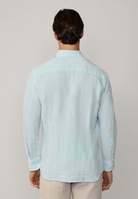 Light blue long-sleeve shirt made of linen, featuring a button-down collar, a smooth texture, and a straight back design.