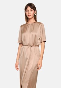 Beige silk dress with short sleeves, relaxed fit, and a tie waistband. Features a smooth texture and flowing fabric, ideal for various occasions.