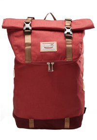 Sac à dos rouge à rabat roulé avec des bretelles marron, des fermetures à boucle argentées, une poche zippée à l'avant et un patch de marque rectangulaire sur le rabat avant.