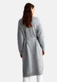 Cardigan lungo grigio lavorato a maglia con cintura in vita, caratterizzato da un motivo testurizzato e polsini e orlo a coste, progettato per una vestibilità rilassata.