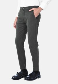 Chinos verde scuro con una vestibilità slim, tasche anteriori e un tessuto in cotone misto liscio, abbinati a mocassini neri lucidi e calzini neri.