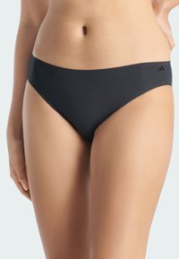 Parte inferior de bikini negra con una textura suave y mate. Presenta un diseño de cintura baja y estilo minimalista, acentuada por un pequeño logo en la cinturilla.