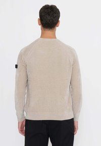 Beiger Pullover mit strukturiertem, geripptem Design an Schultern und Bündchen. Hergestellt aus einem weichen Stoff, verfügt er über einen klassischen Rundhalsausschnitt.
