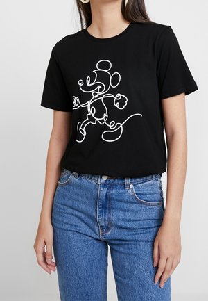 Frau trägt schwarzes T-Shirt mit weißer durchgehender Linienzeichnung einer laufenden Maus, kombiniert mit blauen Jeans.