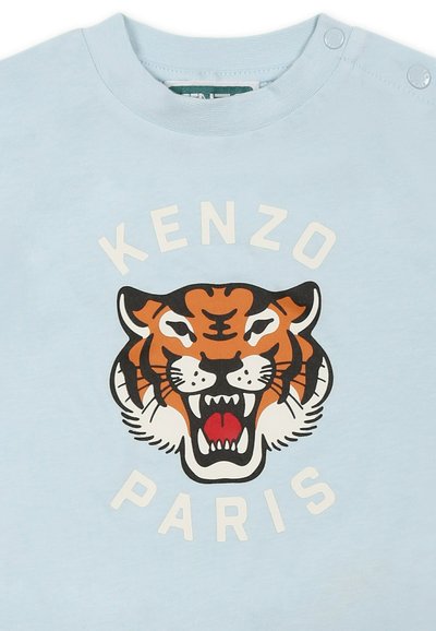 T-shirt en coton bleu clair avec un grand graphisme d'un tigre rugissant en orange, noir et blanc, avec le texte "KENZO PARIS" en blanc en dessous.