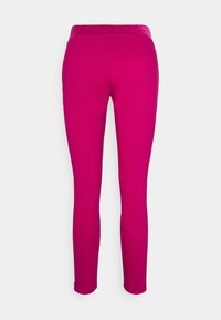 Getailleerde legging in een levendige fuchsia kleur met een soepele tailleband, gepresenteerd tegen een witte achtergrond.