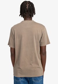 Brązowa koszulka z krótkim rękawem, wykonana z miękkiej bawełny, z okrągłym dekoltem i neutralnym kolorem, z prostym przeszyciem wzdłuż dołu.