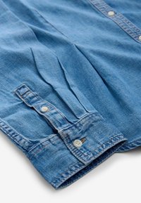 Blauwe denim overhemd met knopen langs de voorkant, lange mouwen met knopenmanchetten en een licht gestructureerde stofafwerking.