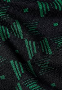 Musta kangas, jossa on teksturoitu pinta, esittää vihreää geometristä kuviointia, joka koostuu vaihtelevaan kokoon ja suuntaan sijoitetuista nauhoista ja neliöistä.