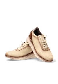 Zapatos de ante beige con puntera redonda, diseño de cordones y un acento marrón claro en el talón. Suela de goma ligeramente elevada para mayor comodidad.