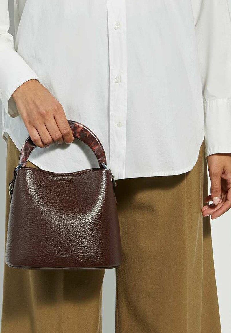 Sac à main en cuir marron avec une surface texturée, doté d'une anse au motif en écaille de tortue. Le sac a une forme arrondie et des accents en métal argenté.