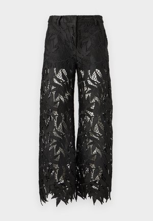 Pantalon noir avec un motif de dentelle à feuilles, coupe large et tissu transparent. Les bords sont festonnés, mettant en valeur les détails complexes.