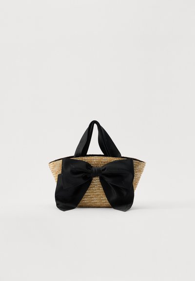 Borsa tote in paglia intrecciata con un accento in raso nero. Presenta due manici in tessuto e un design senza chiusura. Materiale naturale dalla texture interessante.