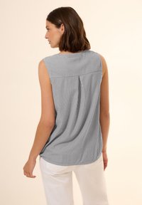 Débardeur sans manches en rayures verticales bleu marine et blanches, présentant une coupe décontractée, un ourlet arrondi et des plis subtils au dos.
