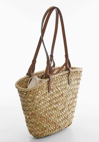 Tkany słomiany torba typu tote z dwoma brązowymi skórzanymi uchwytami, otwartym wierzchem i widoczną jasną podszewką. Teksturowane naturalne wykończenie.