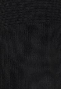 Lähikuva mustasta kudotusta kankaasta, jossa on voimakkaasti uritettu ja rouhea pinta.