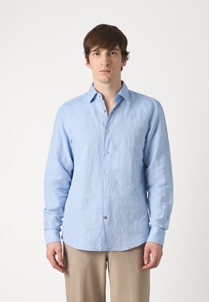 Camicia button-up in lino azzurro chiaro con maniche lunghe, morbida al tatto e con orlo arrotondato, caratterizzata da piccoli bottoni e un colletto classico.