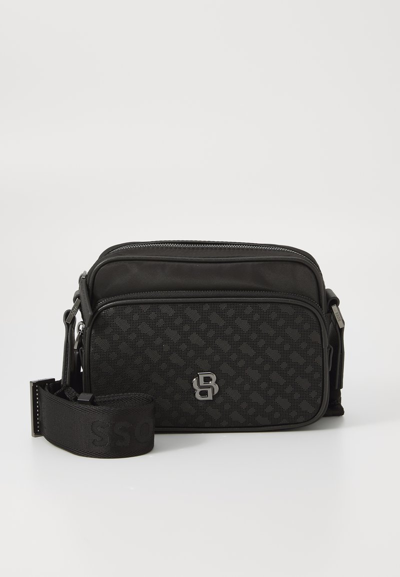 Borsa messenger in tessuto nero con un motivo testurizzato, tracolla regolabile e accessori in argento. Presenta un compartimento con zipper e dettaglio del logo.
