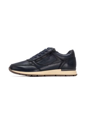 Deportiva de caña baja de cuero en azul marino oscuro con un acabado texturizado, que presenta una cremallera decorativa, cordones redondos y una suela de goma beige.
