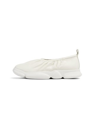 White slip-on shoes with a soft, textured upper and elastic gathering at the opening; thick, cushioned white sole.